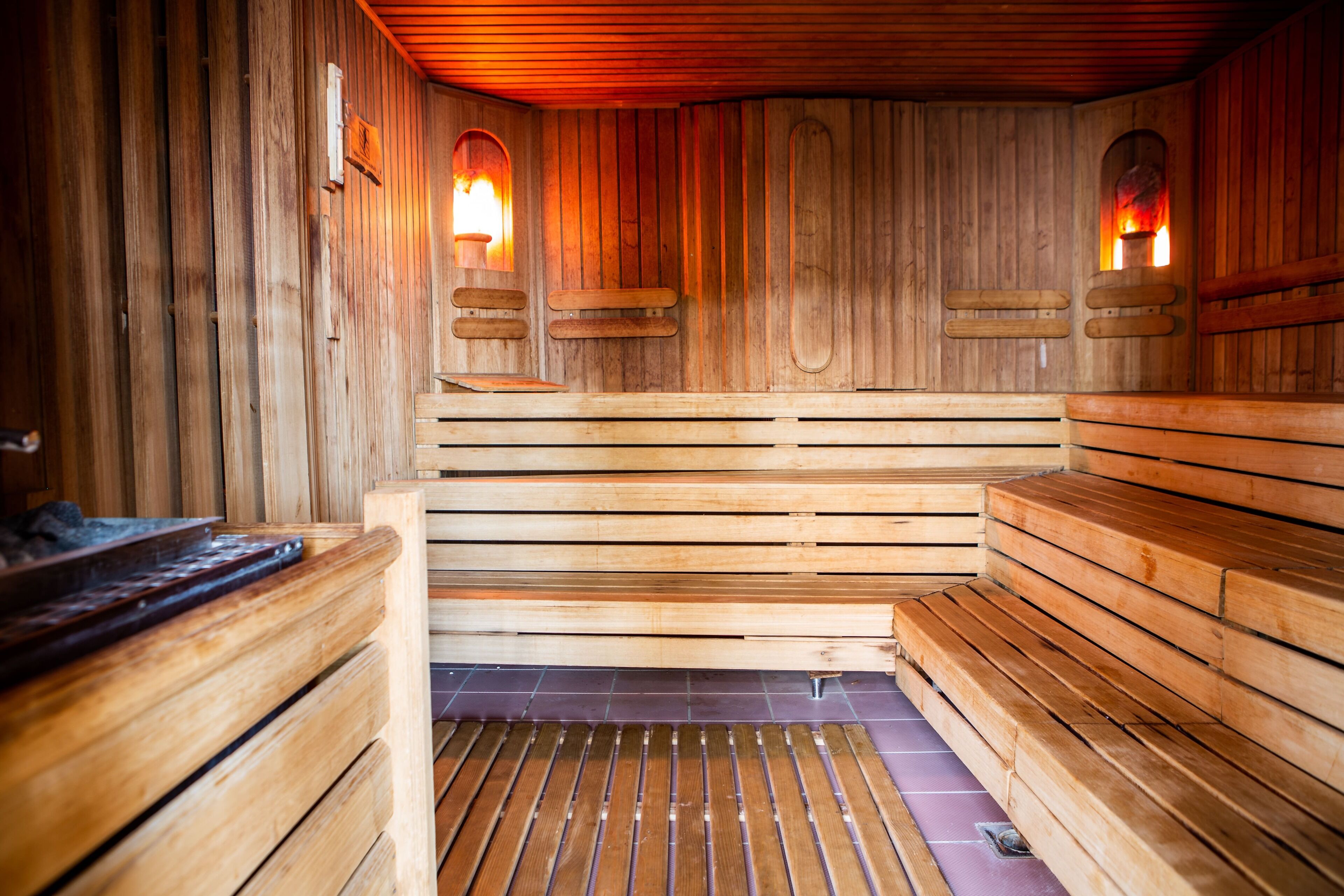 Een houten sauna met banken en twee wandlampen.