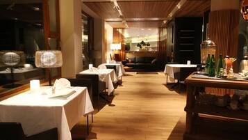 En hotellrestaurang med dukade bord, en soffa i bakgrunden och ett trägolv.