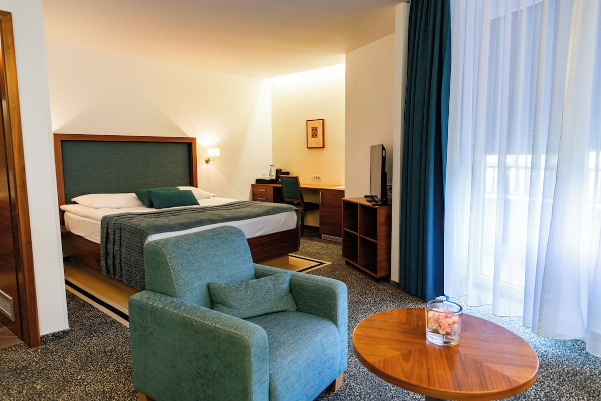 Une chambre d’hôtel équipée d’un lit, d’un bureau, d’une chaise, d’une télévision et d’une fenêtre avec des rideaux.
