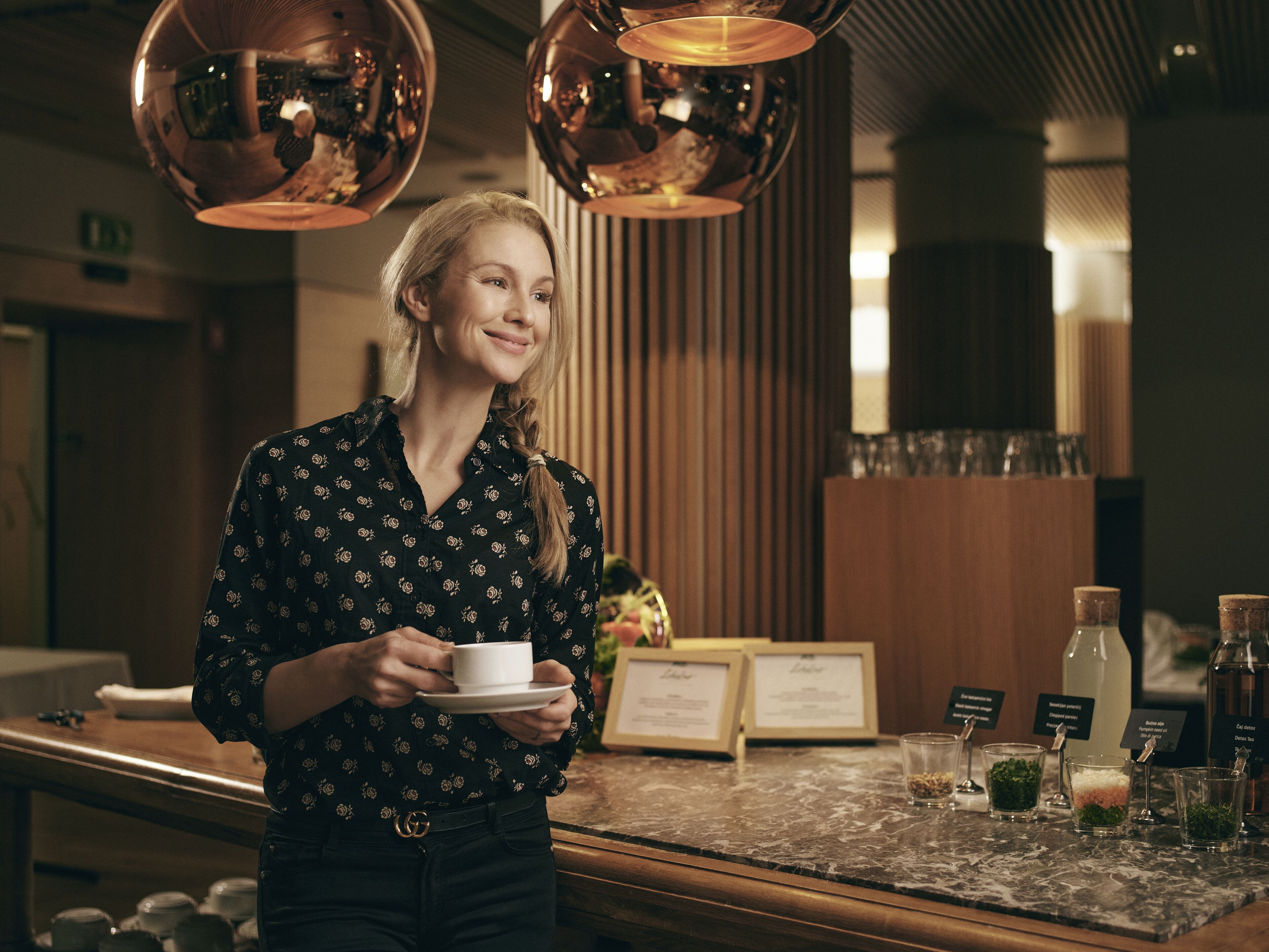 A person standing at a counter with a cup, holding a menu, and various drink dispensers.