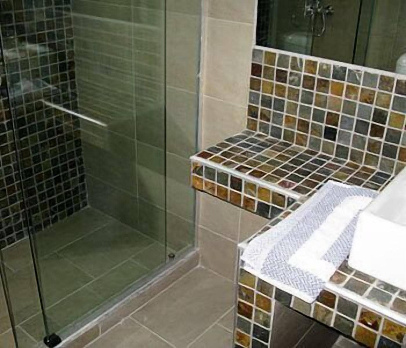 Une salle de bain avec une douche à parois de verre et un meuble-lavabo carrelé.
