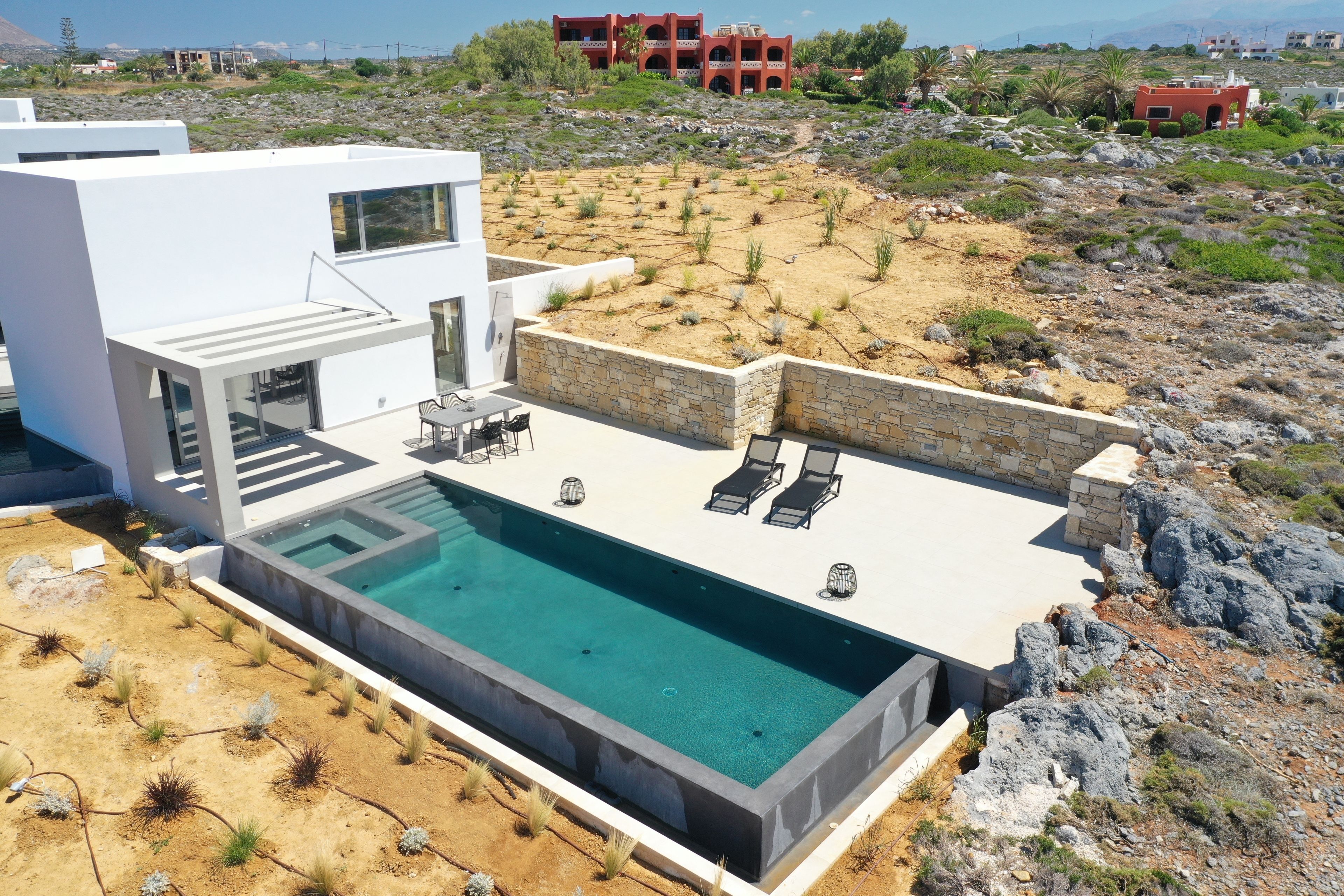 Una casa moderna con piscina, mobiliario exterior y vistas del paisaje circundante.