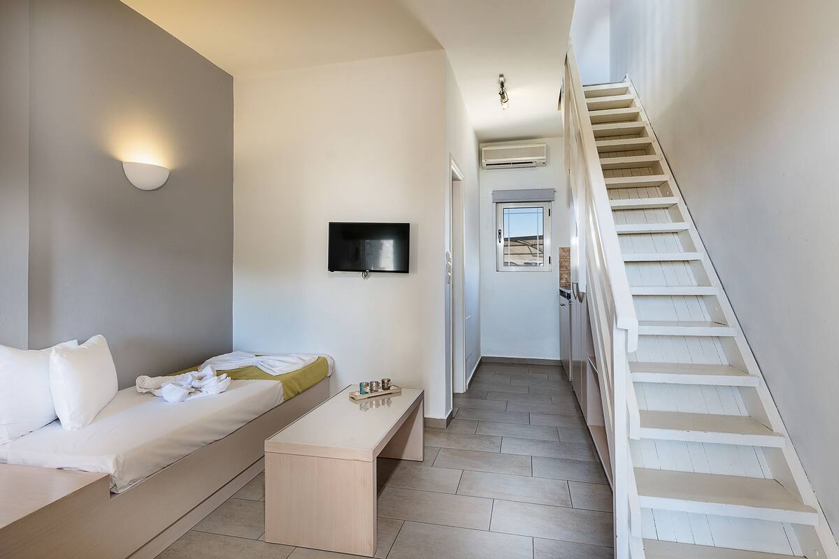 Una habitación de hotel moderna con una cama, una mesita de noche y un televisor montado en la pared.