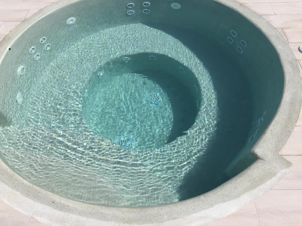 A circular hot tub with a textured interior and a light-colored exterior.