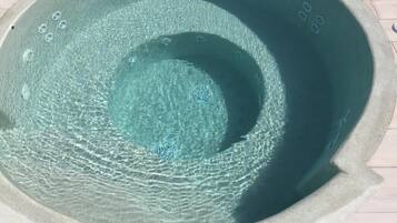A circular hot tub with a textured interior and a light-colored exterior.