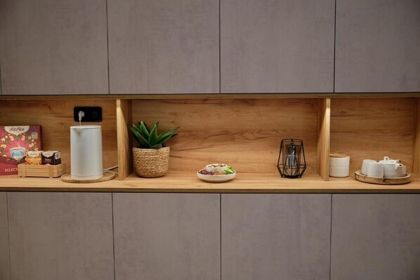 A wooden shelf with various items including a white candle, a potted plant, a small dish, and some kitchenware. - Kavos Hotel (Chania)