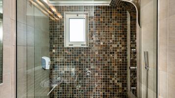 Ducha con puerta de vidrio, ventana y pared con azulejos.