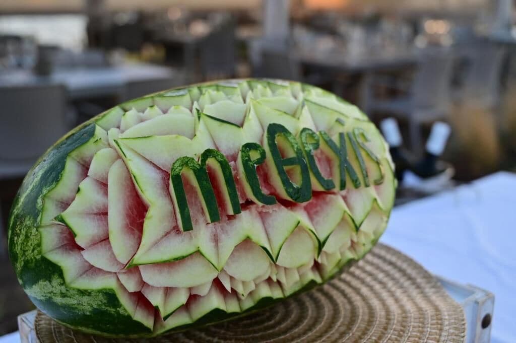 A watermelon carved with the word "MEGA" and a decorative pattern.
