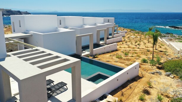 A modern white building with a pool and a view of the sea. - Kavos Hotel (Chania)