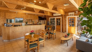 A wooden cabin interior with a kitchen, dining area, and living room. - Logos hotel in Yad Hashmona (Mateh Yehuda)