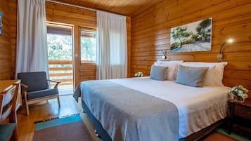 Camera da letto in una baita di legno, con un letto, una sedia e un quadro appeso al muro.