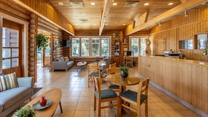 A log cabin interior with a dining area, kitchen, and living room. - Logos hotel in Yad Hashmona (Mateh Yehuda)
