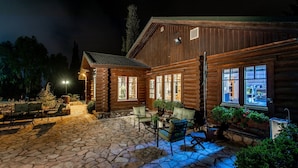 A log cabin with a stone patio, outdoor seating, and large windows. - Logos hotel in Yad Hashmona (Mateh Yehuda)