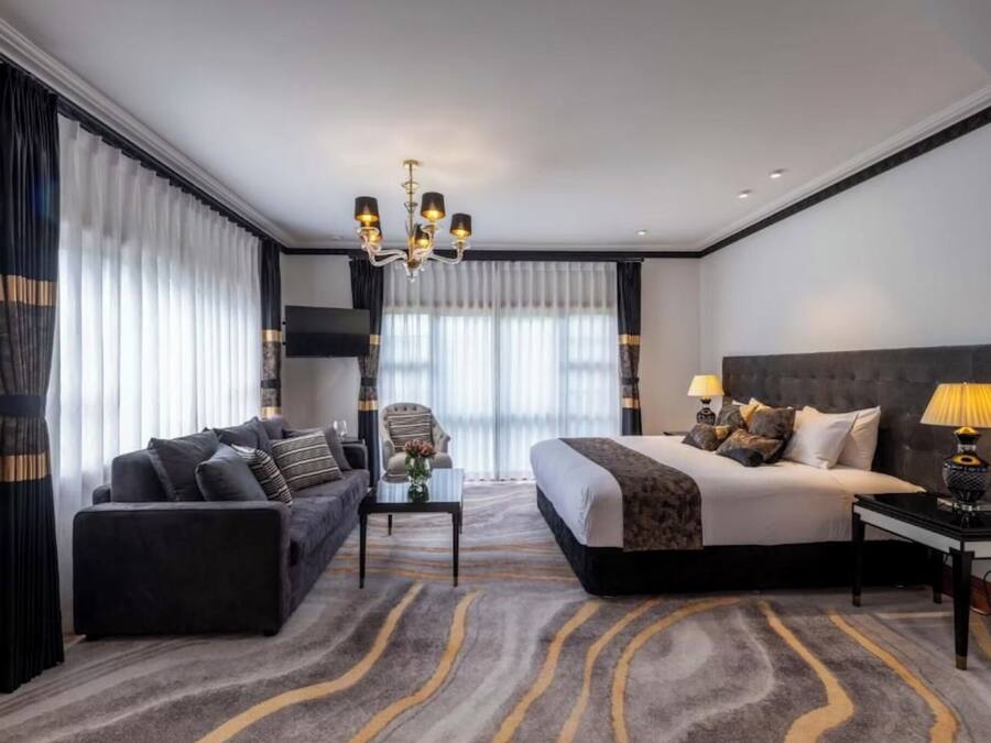 Una habitación de hotel con cama, sofá, mesita de centro, lámpara y candelabro.