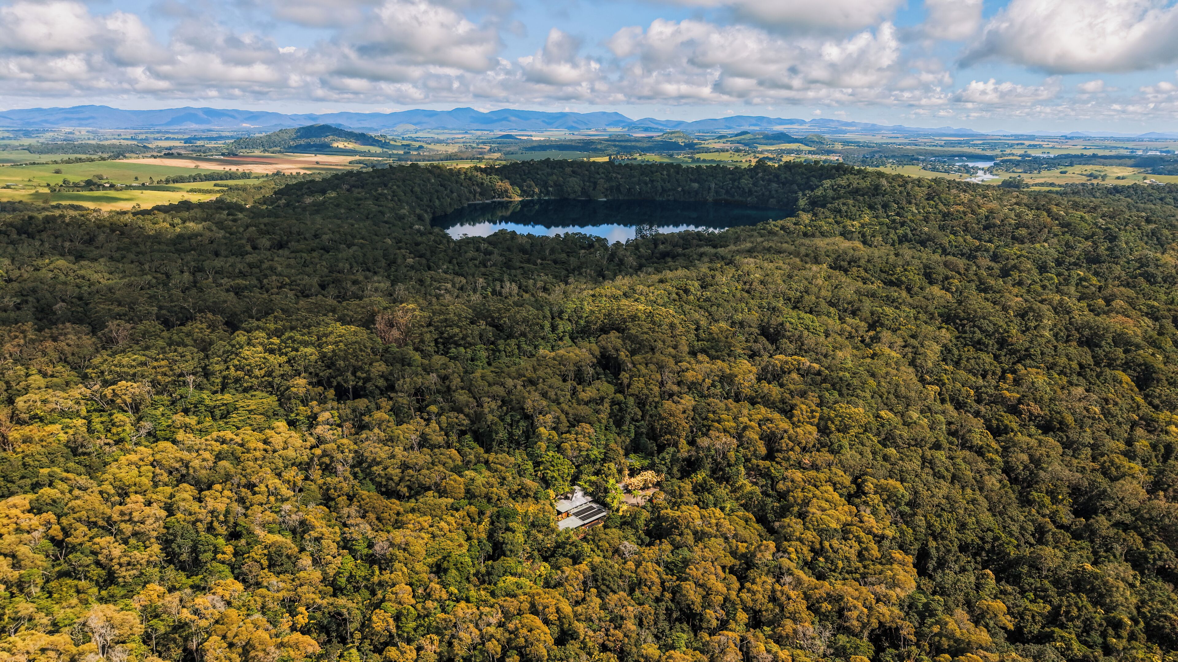 Un área boscosa con un lago y un edificio pequeño.