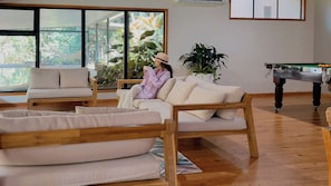 Una habitación con piso de madera, un sofá, una mesa de comedor y un ventanal con vistas a áreas verdes.