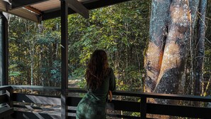 Una persona de pie junto a una barandilla con vista a un bosque frondoso.