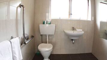 A bathroom with a toilet, sink, and window.