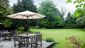 A patio with a table and chairs, surrounded by a lush garden and a well-maintained lawn. - The Eastbury Hotel (Sherborne)
