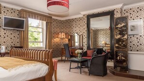 A hotel room with a large bed, a desk, a chair, a television, and a mirror. - The Eastbury Hotel (Sherborne)