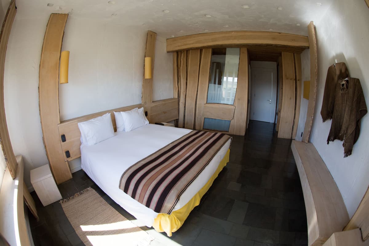 A room with a large bed, wooden headboard, and a small bedside table.