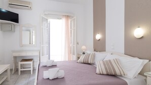 Un dormitorio con cama, mesitas de noche, escritorio, silla, aire acondicionado y ventana con cortinas.