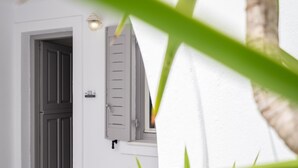 Un edificio blanco con puerta, contraventanas y una lámpara.