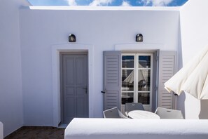 A white room with a door, a window with shutters, and a table with chairs. - Joseph Studios (Paros)