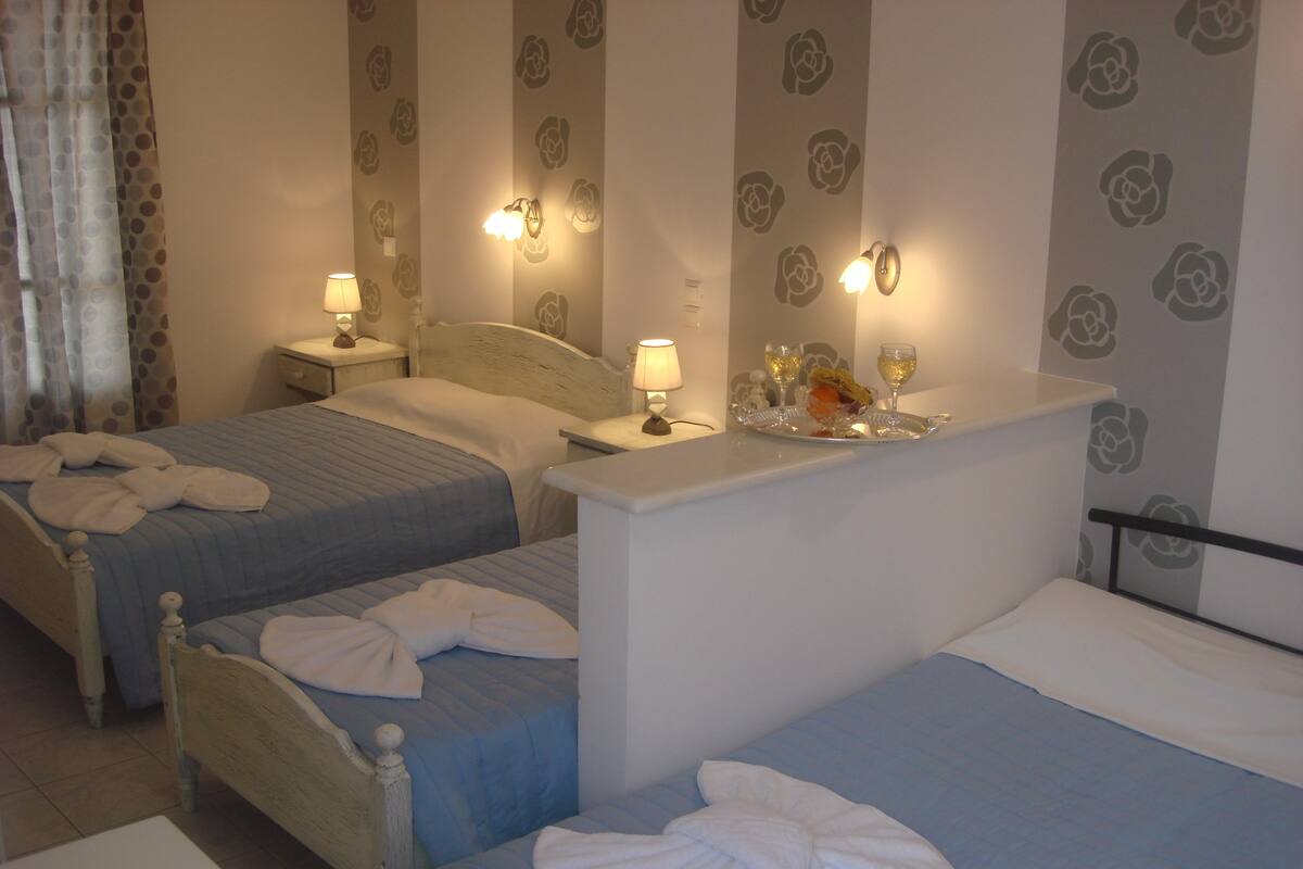 A hotel room with two beds, a small table with a tray of food and drinks, and wall-mounted lamps.