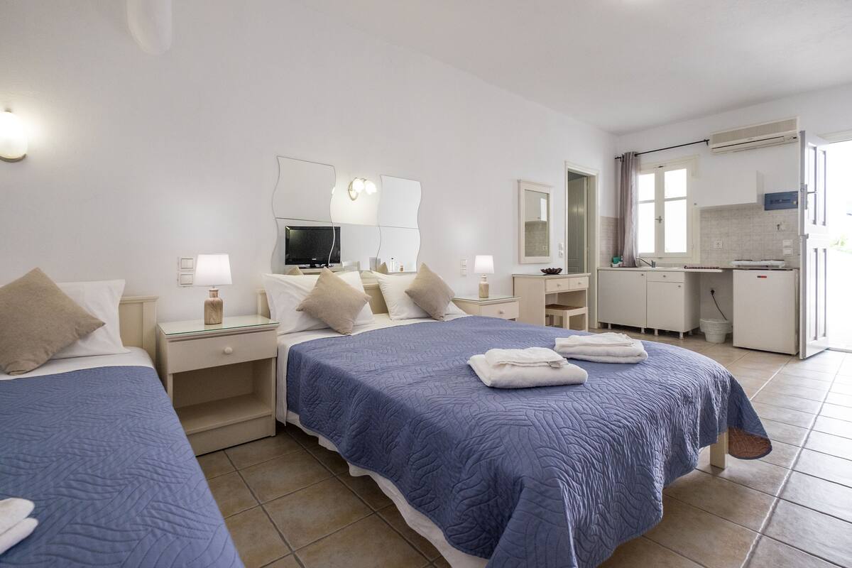 A hotel room with two beds, a television, a desk, and a bathroom.