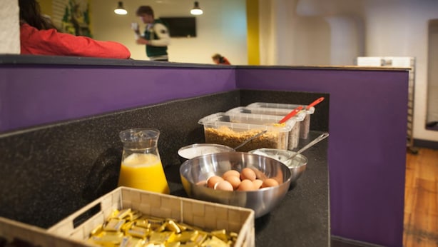 A breakfast bar with containers of cereal, eggs, and juice. - Ashfield Hostel (Dublin)