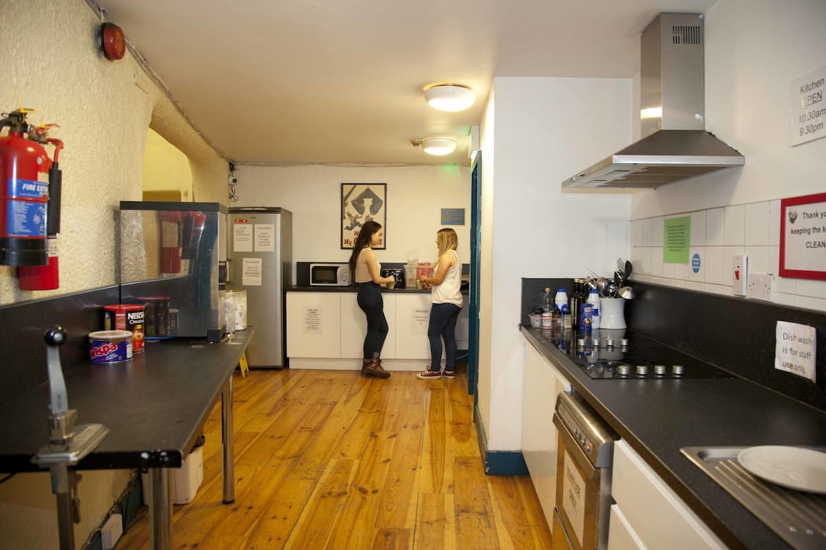 Una cocina con pisos de madera, un extintor, un microondas y un lavamanos.