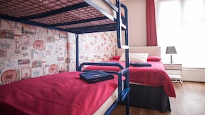 A dormitory room with bunk beds, a patterned wallpaper, a red curtain, and a bedside table with a lamp. - Ashfield Hostel (Dublin)