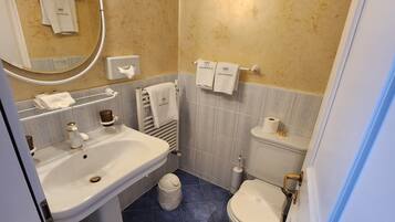 A bathroom with a sink, toilet, and towel rack.