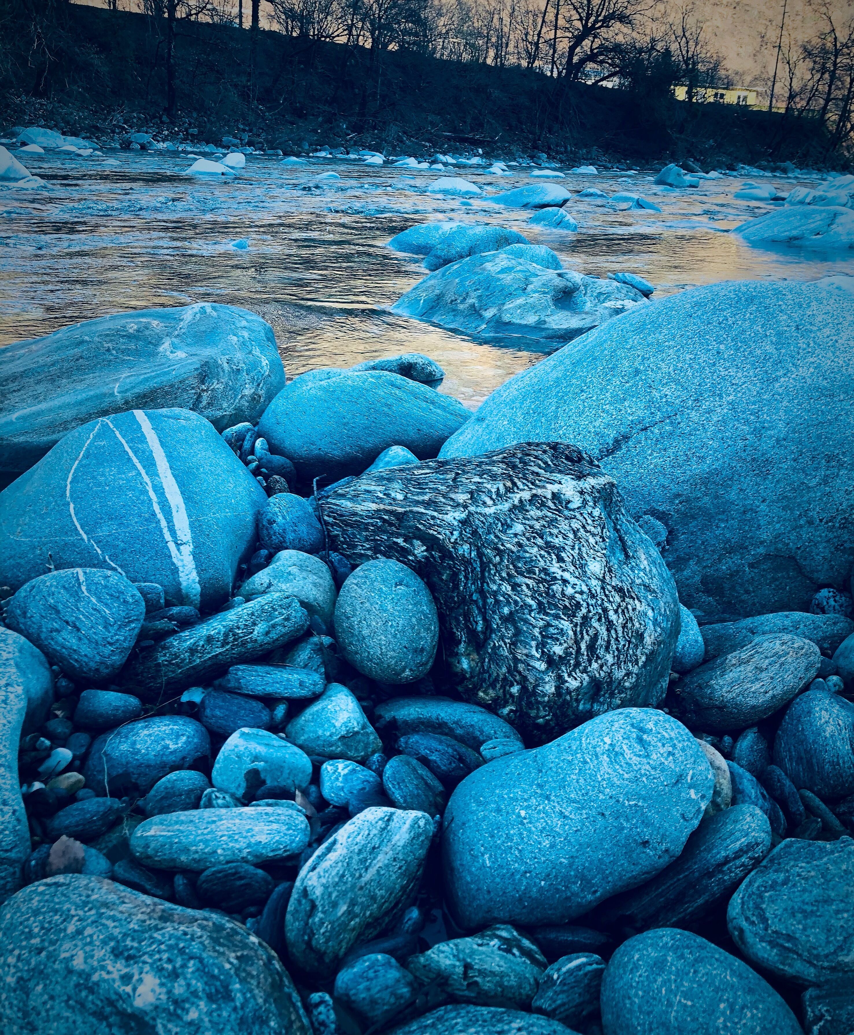 Un lecho fluvial pedregoso con grandes rocas y un río que lo atraviesa.