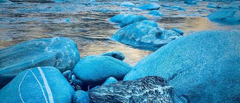 Un lecho fluvial pedregoso con grandes rocas y un río que lo atraviesa.