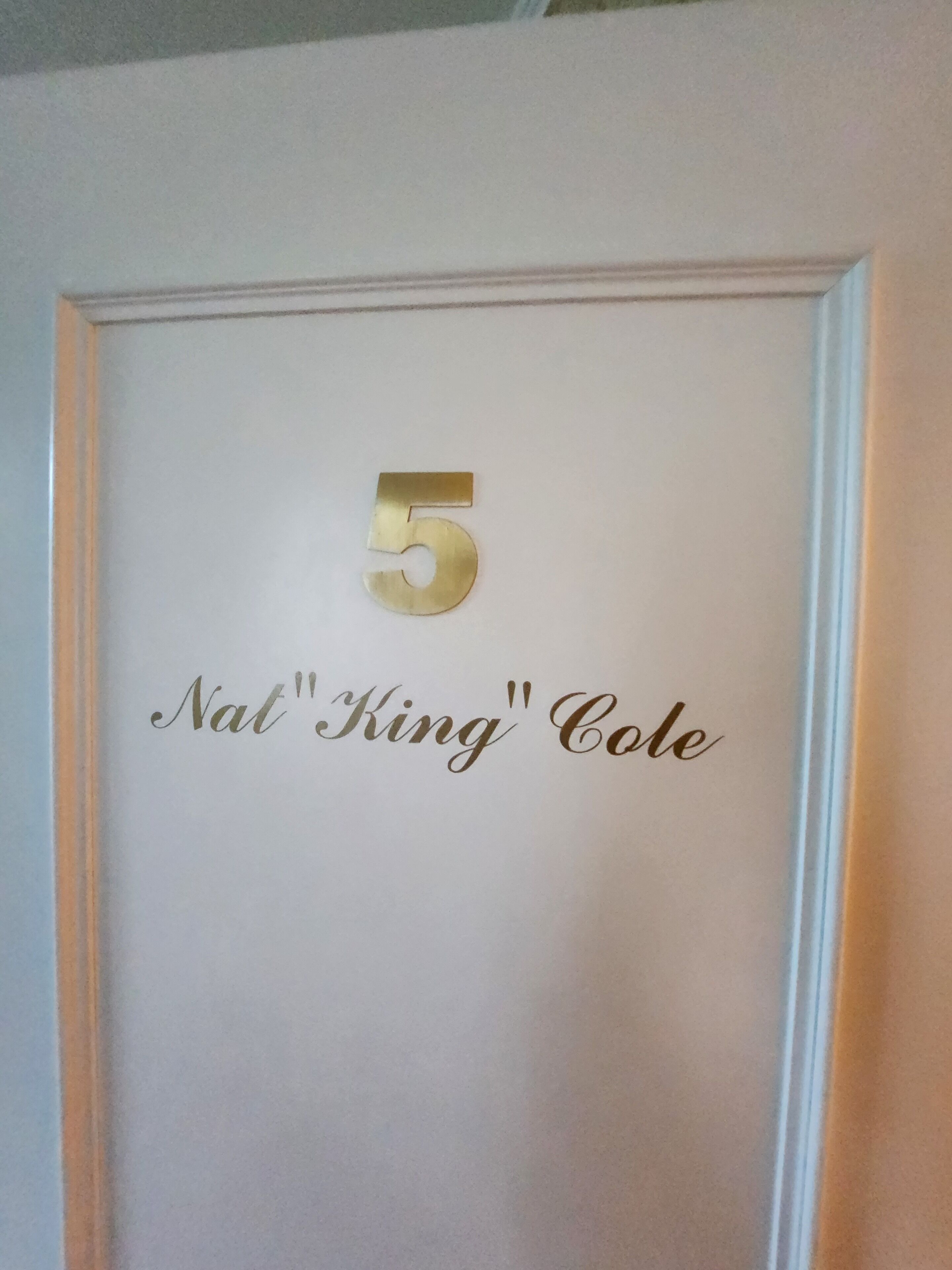 Una puerta con el número 5 y la inscripción 'Nat"King" Cole' en letras doradas.