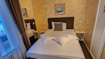 Una habitación de hotel con una cama grande, dos mesitas de noche, una lámpara de noche, un reloj de pared y una ventana con cortinas.
