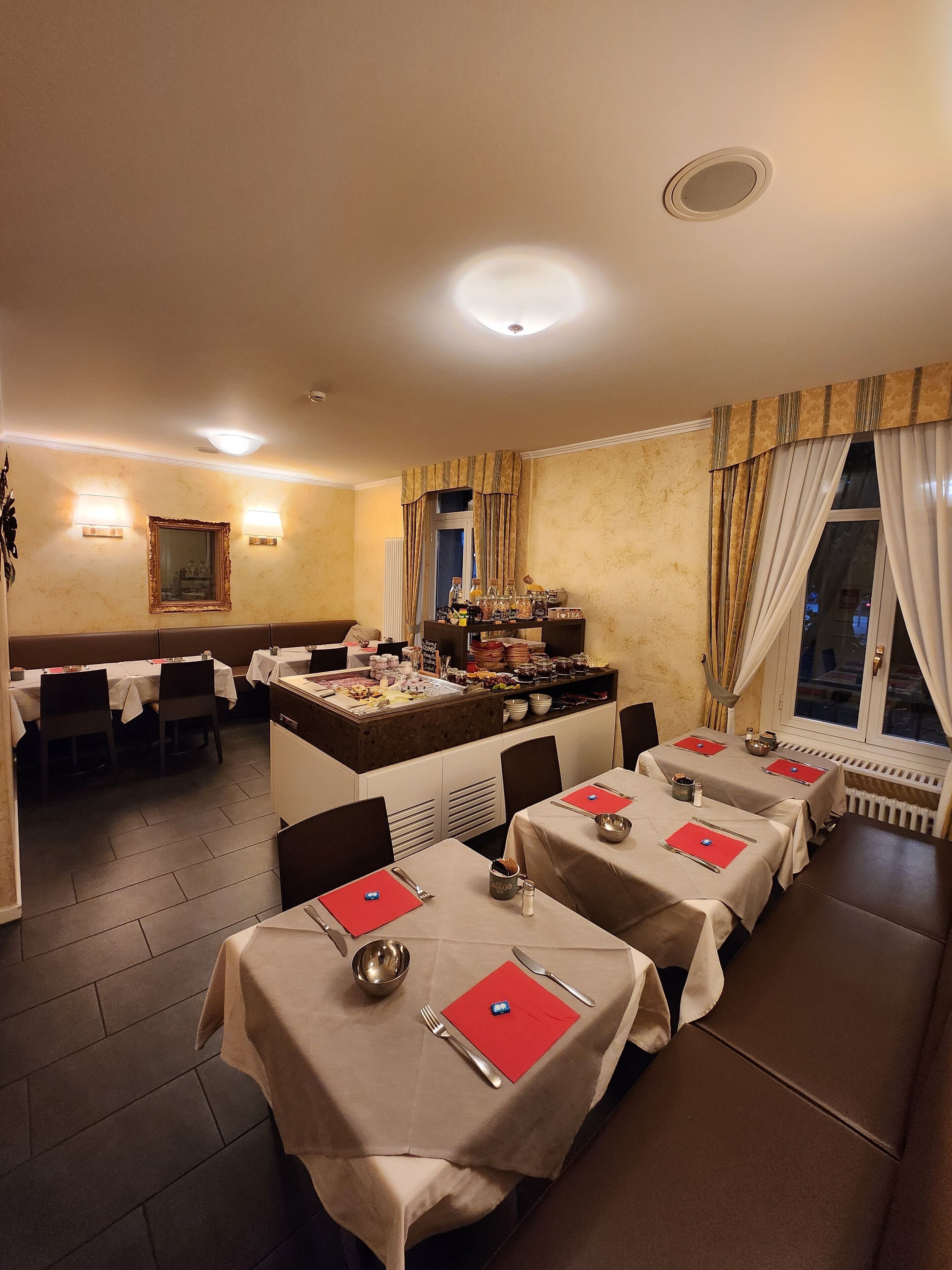 Ein Restaurant mit gedeckten Tischen, einem Buffet und Blick durch ein Fenster nach draußen.