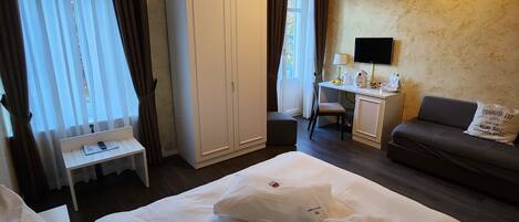Habitación de hotel con dos camas, un escritorio, un sofá y un armario.