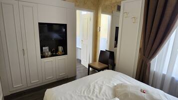 A hotel room with a bed, a TV, a chair, and a wardrobe.
