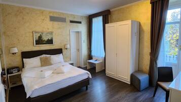 A hotel room with a large bed, a wardrobe, a desk, and a chair.