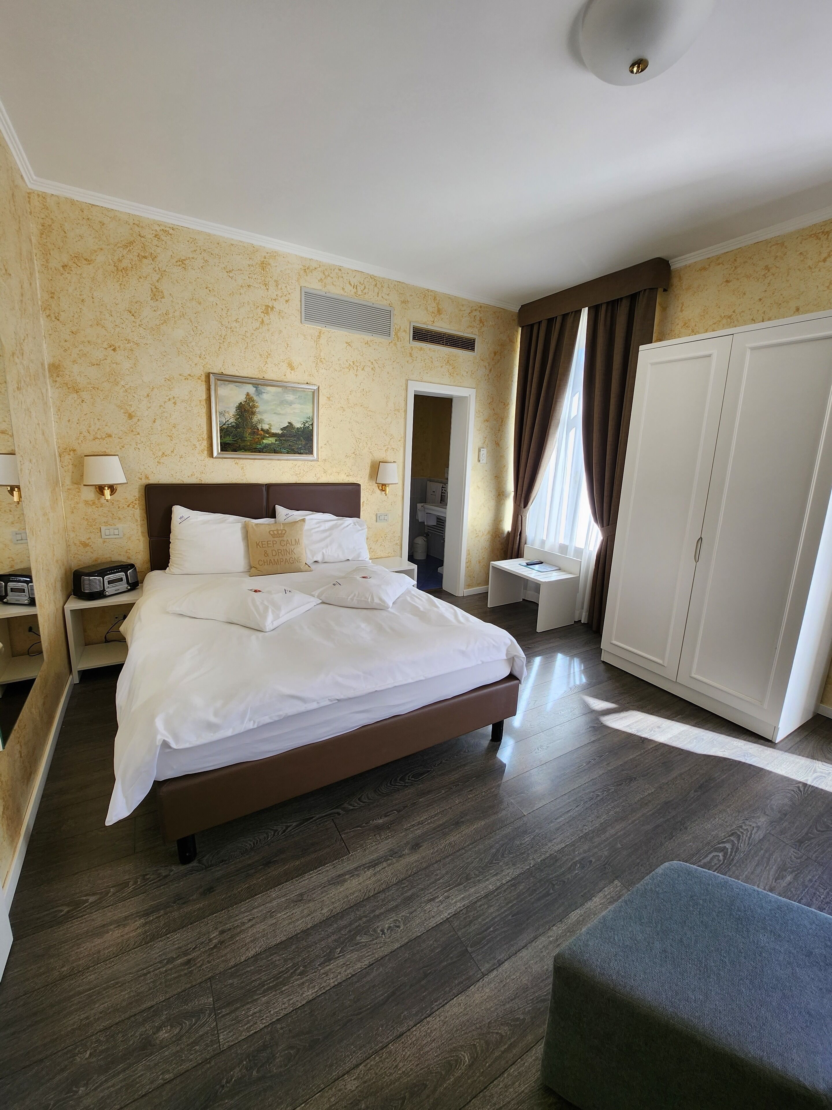 Une chambre d’hôtel avec un grand lit, des tables de chevet, une armoire et une vue sur l’extérieur.