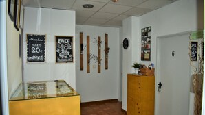 A hallway with a glass display case, wooden cabinets, and a door marked with the number 6. - Pension Castil (Granada)