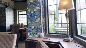 Une pièce meublée de mobilier en osier, avec un mur orné d’un motif et une fenêtre agrémentée d’une lampe.