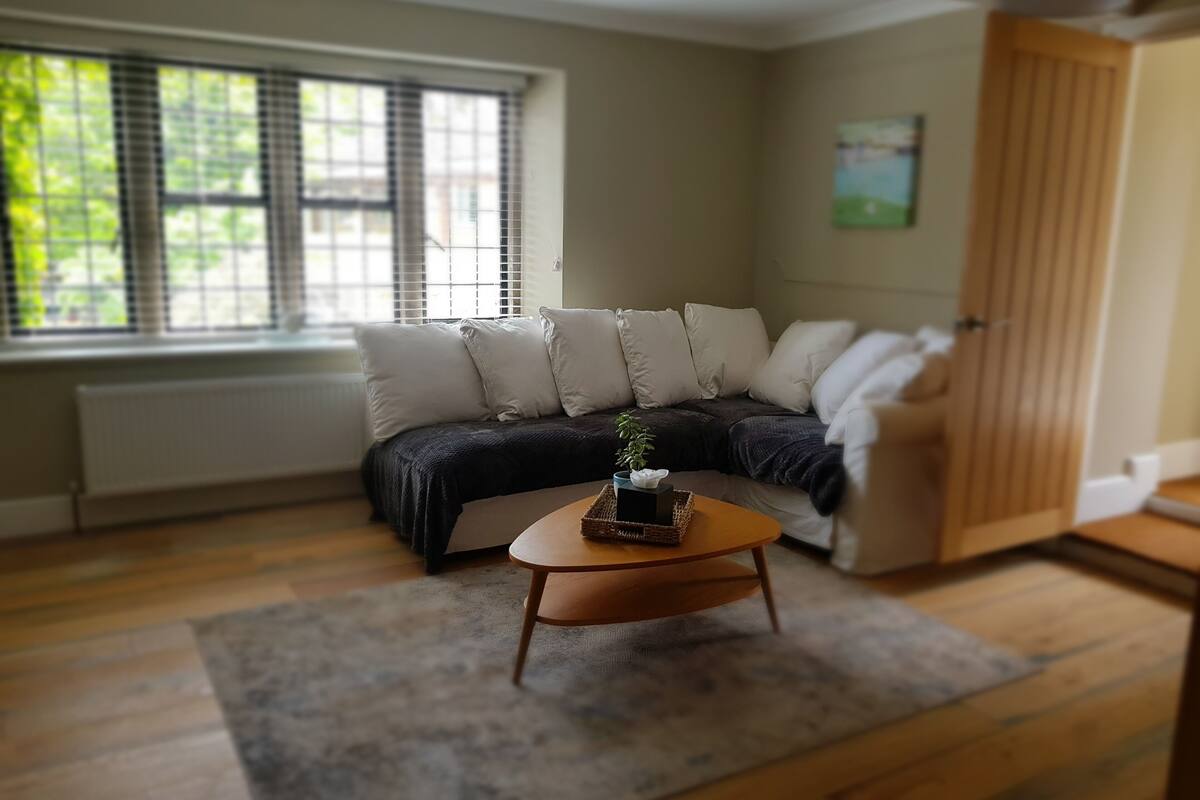 A living room with a sofa, a coffee table, and a window with blinds.