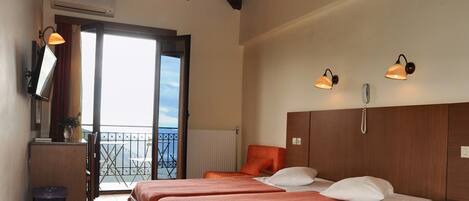 Une chambre d’hôtel avec deux lits, un plafond en bois, un balcon avec vue et des lampes fixées au mur.
