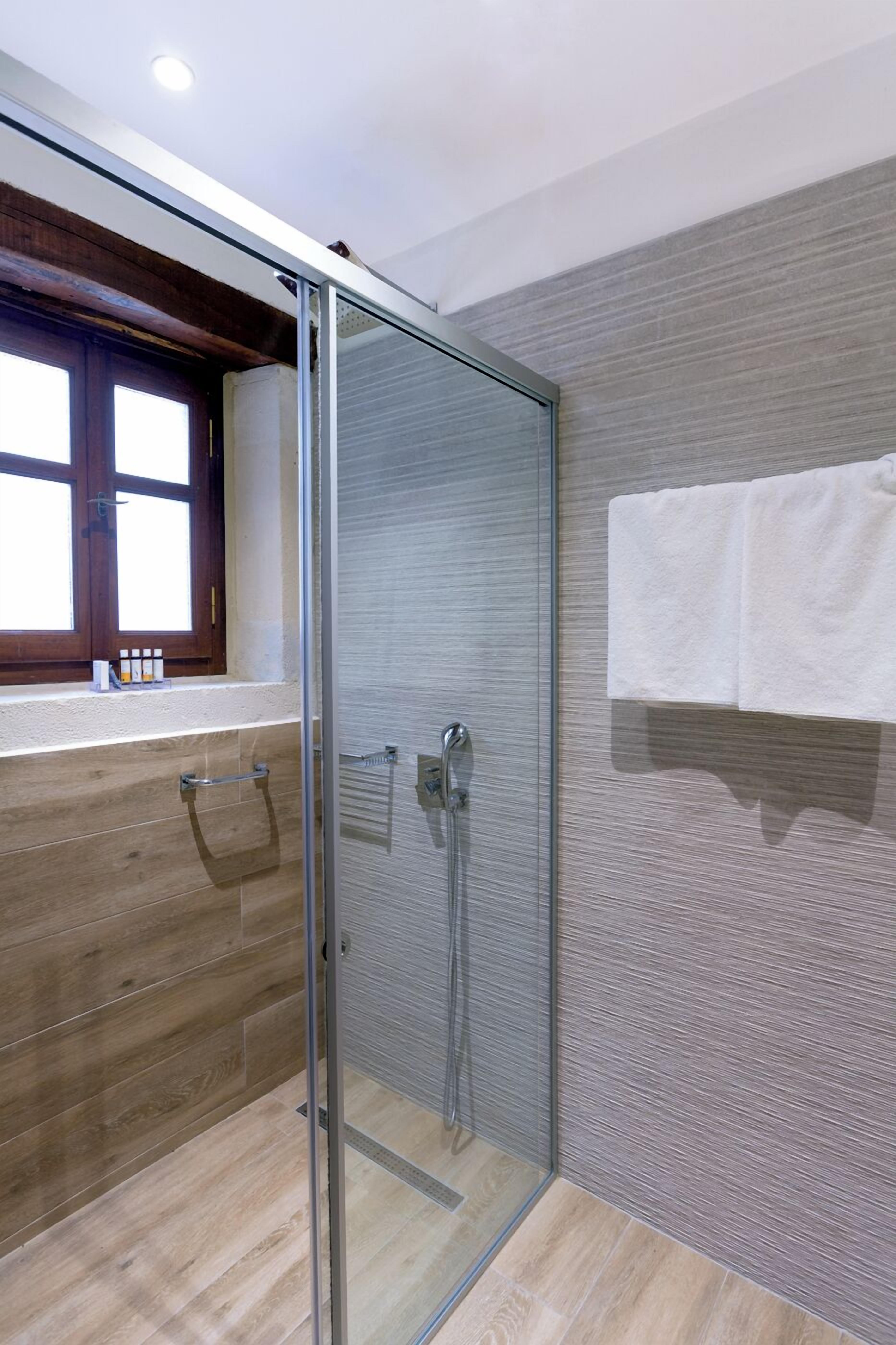 A modern bathroom with a glass shower enclosure, wooden vanity, and a towel rack.