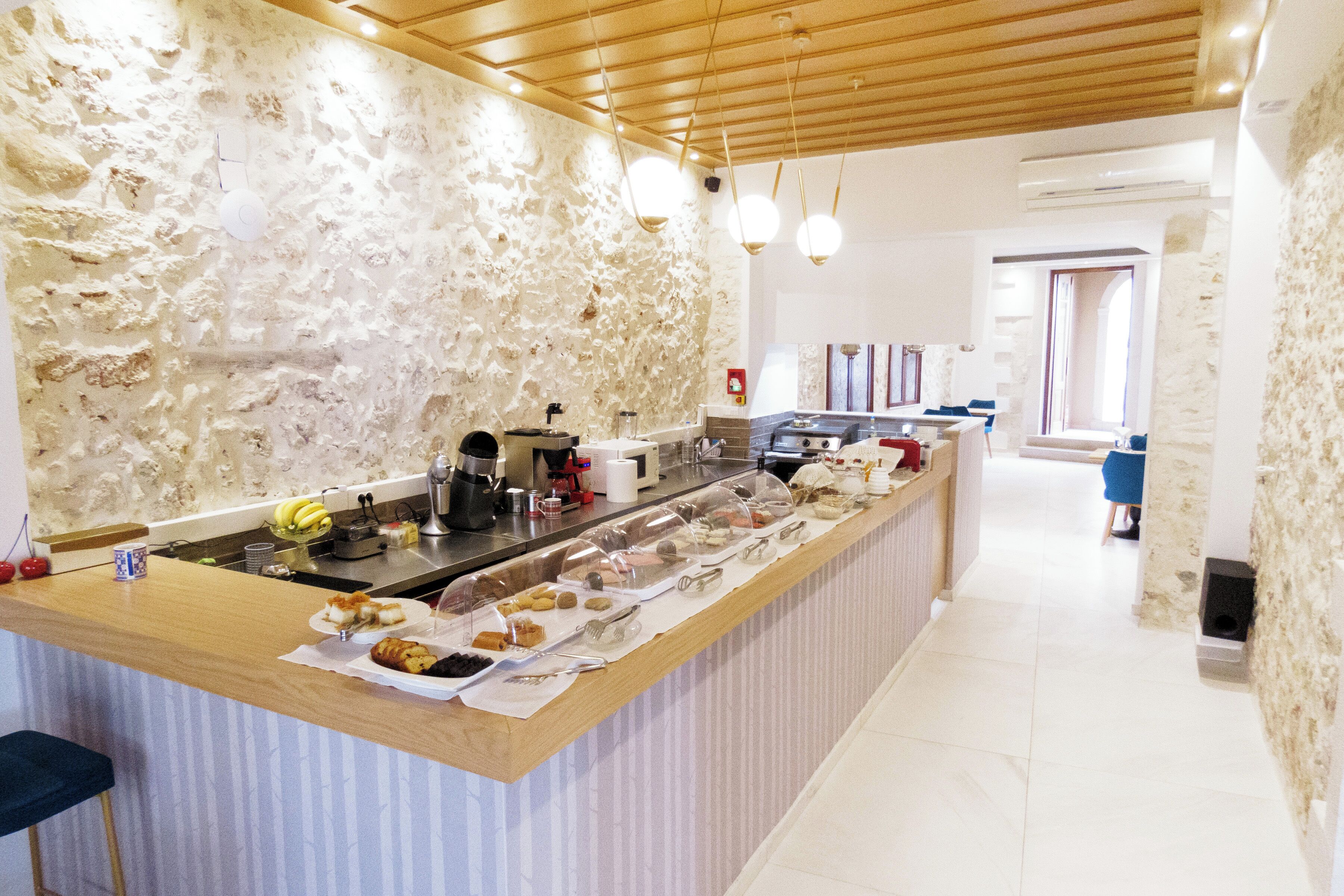 A kitchen with a stone wall, wooden ceiling, and a buffet counter with various food items.