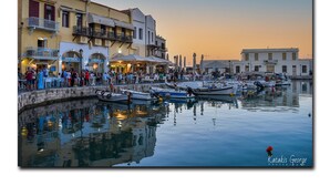 A waterfront area with boats docked, a crowd of people, and buildings with outdoor seating. - Hotel Casa Moazzo (Rethymno)